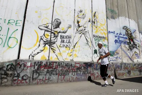 A participant runs past the controversial Israeli barrier during the annual Right to Movement Palestine Marathon in the West Bank town of Bethlehem April 1, 2016. Photo by Wisam Hashlamoun