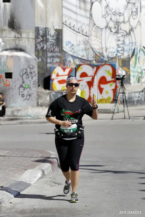 A participant runs near the controversial Israeli barrier during the annual Right to Movement Palestine Marathon in the West Bank town of Bethlehem April 1, 2016. Photo by Wisam Hashlamoun