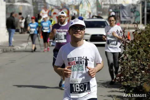 Participants run past the controversial Israeli barrier during the annual Right to Movement Palestine Marathon in the West Bank town of Bethlehem April 1, 2016. Photo by Wisam Hashlamoun