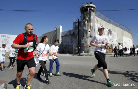 Participants run past the controversial Israeli barrier during the annual Right to Movement Palestine Marathon in the West Bank town of Bethlehem April 1, 2016. Photo by Wisam Hashlamoun