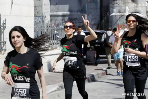 Participants run past the controversial Israeli barrier during the annual Right to Movement Palestine Marathon in the West Bank town of Bethlehem April 1, 2016. Photo by Wisam Hashlamoun