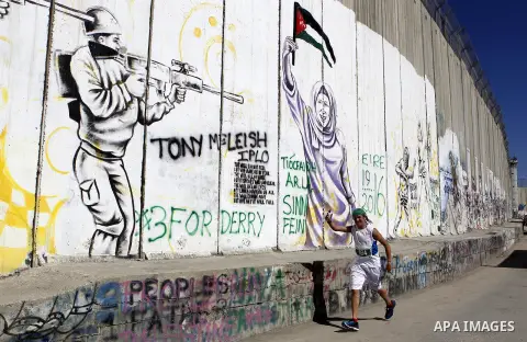 A participant runs past the controversial Israeli barrier during the annual Right to Movement Palestine Marathon in the West Bank town of Bethlehem April 1, 2016. Photo by Wisam Hashlamoun