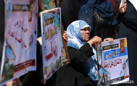 Palestinian women hold banners during a rally marking Land Day, near Eriz crossing in the northern Gaza Strip, on April 2, 2016. Photo by Yasser Qudih