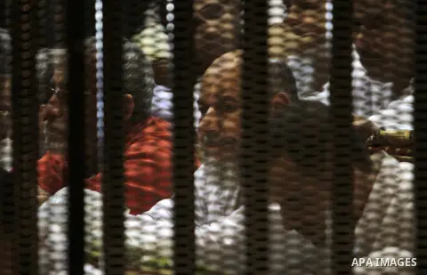 Muslim Brotherhood members sit behind the defendants cage as they attend their trial along with Egyptian Muslim Brotherhood leader Mohammed Badie (unseen), at a court in the outskirts of Cairo, Egypt, on April 03, 2016....