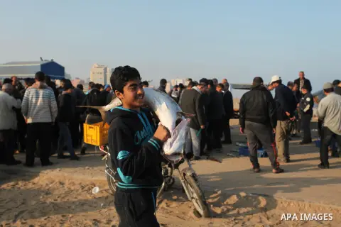 A Palestinian boy displays fish for sale, in Gaza seaport, on April 4, 2016. Israel on Sunday extended the distance it permits Gaza fishermen to head out to sea along certain parts of the coastline of the enclave, which...