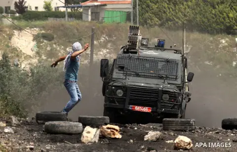 A Palestinian protester hurls stones towards Israeli security forces jeep during clashes following a weekly demonstration against the expropriation of Palestinian land by Israel in the village of Kfar Qaddum, near Nablus...