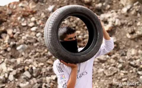 A Palestinian protester carries tires during clashes with Israeli security forces following a weekly demonstration against the expropriation of Palestinian land by Israel in the village of Kfar Qaddum, near Nablus, in th...