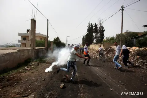 Palestinian protesters run for cover from tear gas fired by Israeli security forces during clashes following a weekly demonstration against the expropriation of Palestinian land by Israel in the village of Kfar Qaddum, n...