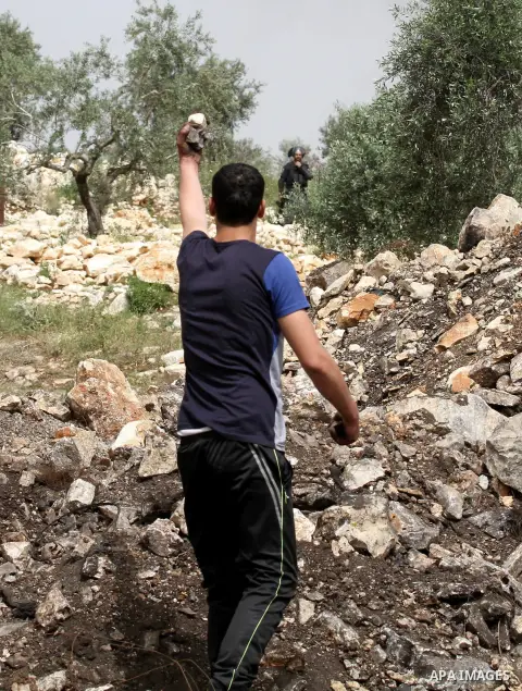 A Palestinian protester carries stones during clashes with Israeli security forces following a weekly demonstration against the expropriation of Palestinian land by Israel in the village of Kfar Qaddum, near Nablus, in t...