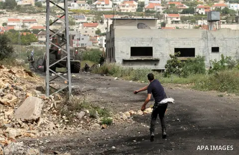 A Palestinian protester hurls stones towards Israeli security forces during clashes following a weekly demonstration against the expropriation of Palestinian land by Israel in the village of Kfar Qaddum, near Nablus, in...