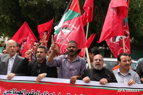 Palestinian supporters of the Democratic Front for the Liberation of Palestine (DFLP) shout slogans and hold banners during a protest against a power cut, in front of the Council of Ministers, in Gaza city, on April 11,...