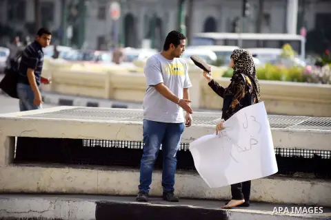 An Egyptian woman argue with an Egyptian protester as he holds placard wrote in arabic "Awwad sold his land" at Tahrir square in Cairo on April 11, 2016. Egypt and Saudi Arabia agreed to maritime borders that handed owne...