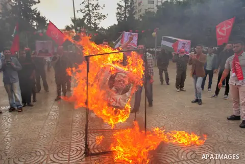 Supporters of the Popular Front for the Liberation of Palestine (PFLP) burn a poster of Palestinian President Mahmoud Abbas during a protest against Abbas's policies, in Gaza City April 12, 2016. The poster reads, "Leave...
