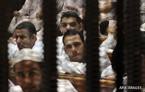 Muslim Brotherhood members sit behind the defendants cage as they attend their trial along with Egyptian Muslim Brotherhood leader Mohammed Badie (unseen), at a court in the outskirts of Cairo, Egypt, on April 12, 2016....