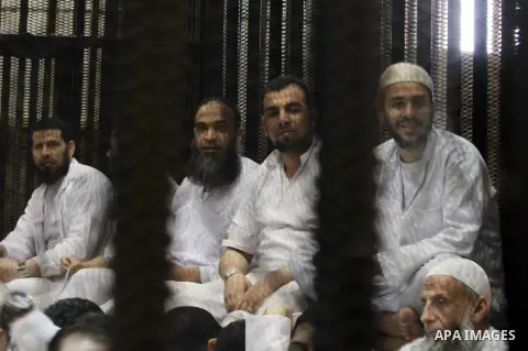 Muslim Brotherhood members sit behind the defendants cage as they attend their trial along with Egyptian Muslim Brotherhood leader Mohammed Badie (unseen), at a court in the outskirts of Cairo, Egypt, on April 12, 2016....