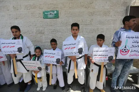 Palestinians hold banners during a protest in solidarity with the karate trainer, Hassan El-Raey against his arrest by the Israeli army, in front of Red cross office in Gaza city on April 13, 2016. Photo by Mohammed Asad