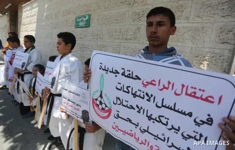 Palestinians hold banners during a protest in solidarity with the karate trainer, Hassan El-Raey against his arrest by the Israeli army, in front of Red cross office in Gaza city on April 13, 2016. Photo by Mohammed Asad