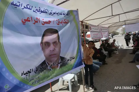 Palestinians hold banners during a protest in solidarity with the karate trainer, Hassan El-Raey against his arrest by the Israeli army, in front of Red cross office in Gaza city on April 13, 2016. Photo by Mohammed Asad