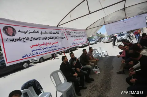 Palestinians hold banners during a protest in solidarity with the karate trainer, Hassan El-Raey against his arrest by the Israeli army, in front of Red cross office in Gaza city on April 13, 2016. Photo by Mohammed Asad
