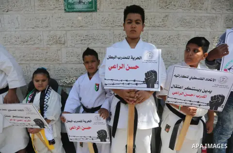Palestinians hold banners during a protest in solidarity with the karate trainer, Hassan El-Raey against his arrest by the Israeli army, in front of Red cross office in Gaza city on April 13, 2016. Photo by Mohammed Asad