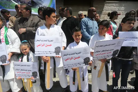 Palestinians hold banners during a protest in solidarity with the karate trainer, Hassan El-Raey against his arrest by the Israeli army, in front of Red cross office in Gaza city on April 13, 2016. Photo by Mohammed Asad