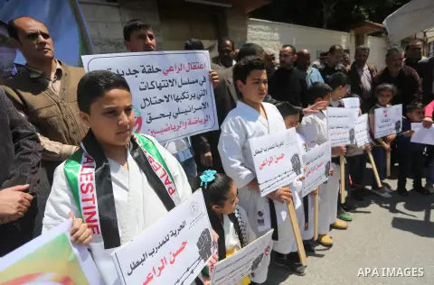 Palestinians hold banners during a protest in solidarity with the karate trainer, Hassan El-Raey against his arrest by the Israeli army, in front of Red cross office in Gaza city on April 13, 2016. Photo by Mohammed Asad