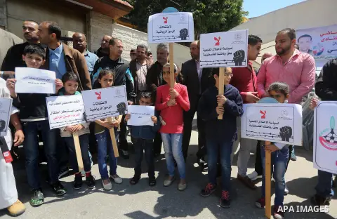 Palestinians hold banners during a protest in solidarity with the karate trainer, Hassan El-Raey against his arrest by the Israeli army, in front of Red cross office in Gaza city on April 13, 2016. Photo by Mohammed Asad
