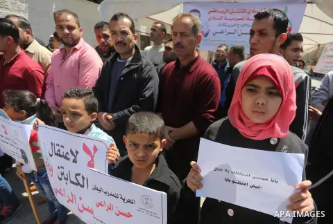 Palestinians hold banners during a protest in solidarity with the karate trainer, Hassan El-Raey against his arrest by the Israeli army, in front of Red cross office in Gaza city on April 13, 2016. Photo by Mohammed Asad