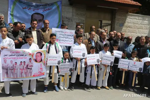 Palestinians hold banners during a protest in solidarity with the karate trainer, Hassan El-Raey against his arrest by the Israeli army, in front of Red cross office in Gaza city on April 13, 2016. Photo by Mohammed Asad