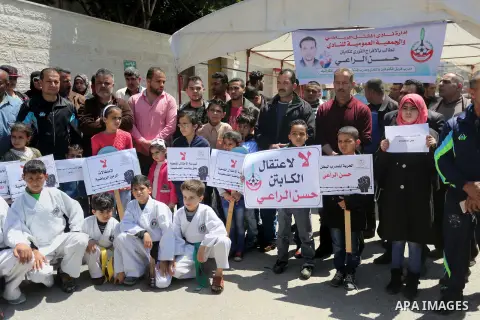 Palestinians hold banners during a protest in solidarity with the karate trainer, Hassan El-Raey against his arrest by the Israeli army, in front of Red cross office in Gaza city on April 13, 2016. Photo by Mohammed Asad