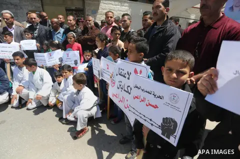 Palestinians hold banners during a protest in solidarity with the karate trainer, Hassan El-Raey against his arrest by the Israeli army, in front of Red cross office in Gaza city on April 13, 2016. Photo by Mohammed Asad