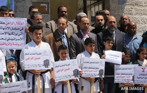 Palestinians hold banners during a protest in solidarity with the karate trainer, Hassan El-Raey against his arrest by the Israeli army, in front of Red cross office in Gaza city on April 13, 2016. Photo by Mohammed Asad