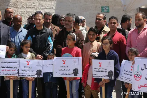 Palestinians hold banners during a protest in solidarity with the karate trainer, Hassan El-Raey against his arrest by the Israeli army, in front of Red cross office in Gaza city on April 13, 2016. Photo by Mohammed Asad