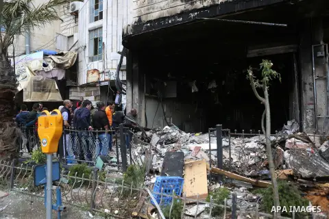 Palestinians gather around a money changer in the Palestinian political capital Ramallah after it was raided by Israeli forces, blowing up a safe and sparking a fire, on April 14, 2016. An Israeli army spokeswoman said t...