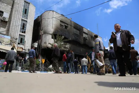 Palestinians gather around a money changer in the Palestinian political capital Ramallah after it was raided by Israeli forces, blowing up a safe and sparking a fire, on April 14, 2016. An Israeli army spokeswoman said t...