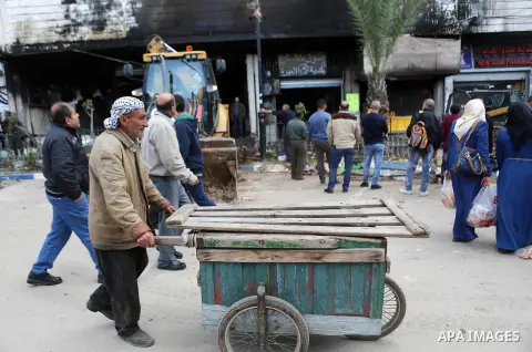 Palestinians gather around a money changer in the Palestinian political capital Ramallah after it was raided by Israeli forces, blowing up a safe and sparking a fire, on April 14, 2016. An Israeli army spokeswoman said t...