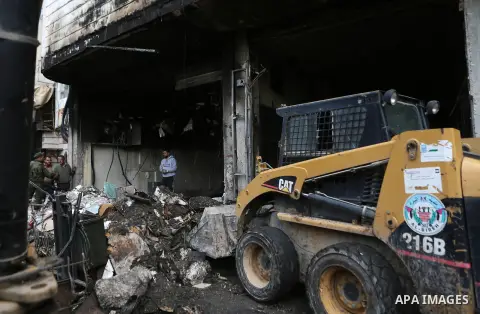 Palestinians check a money changer in the Palestinian political capital Ramallah after it was raided by Israeli forces, blowing up a safe and sparking a fire, on April 14, 2016. An Israeli army spokeswoman said the pre-d...