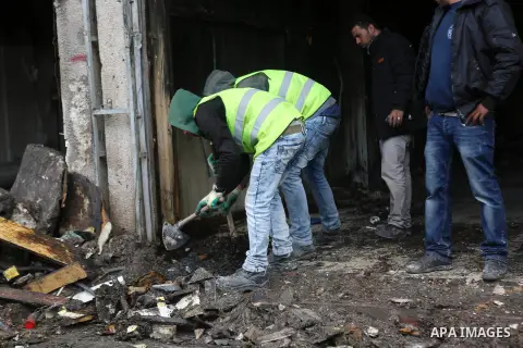 Palestinians check a money changer in the Palestinian political capital Ramallah after it was raided by Israeli forces, blowing up a safe and sparking a fire, on April 14, 2016. An Israeli army spokeswoman said the pre-d...