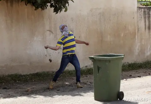 A Palestinian protester uses a slingshot to hurl stones towards Israeli security forces during clashes following a weekly demonstration against the expropriation of Palestinian land by Israel in the village of Kfar Qaddu...
