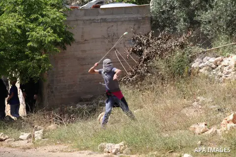 A Palestinian protester uses a slingshot to hurl stones towards Israeli security forces during clashes following a weekly demonstration against the expropriation of Palestinian land by Israel in the village of Kfar Qaddu...