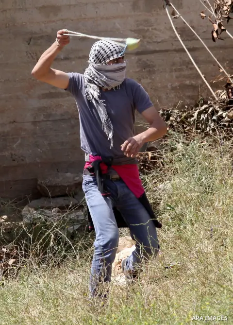 A Palestinian protester uses a slingshot to hurl stones towards Israeli security forces during clashes following a weekly demonstration against the expropriation of Palestinian land by Israel in the village of Kfar Qaddu...