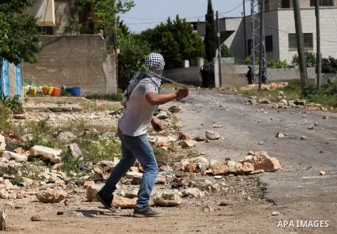 A Palestinian protester uses a slingshot to hurl stones towards Israeli security forces during clashes following a weekly demonstration against the expropriation of Palestinian land by Israel in the village of Kfar Qaddu...