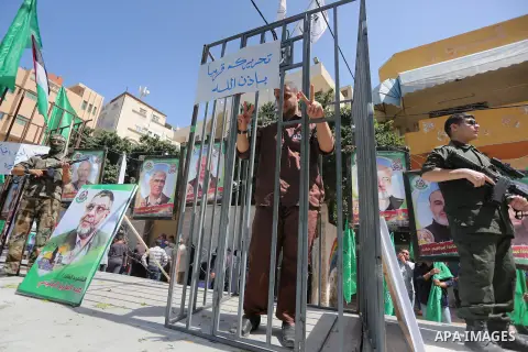 Members of the Ezzedine al-Qassam Brigades, the military wing of the Palestinian Islamist movement Hamas, stand next to mock jails during a rally marking Palestinian Prisoner Day in Gaza City on April 17, 2016. Photo by...