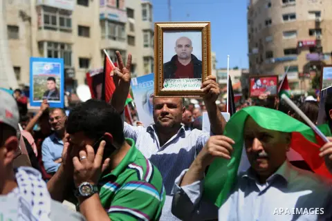 Palestinians hold pictures of Palestinians detained in Israeli prisons during a demonstration to mark Palestinian Prisoner Day in the West Bank city of Ramallah on April 17, 2016. Photo by Shadi Hatem