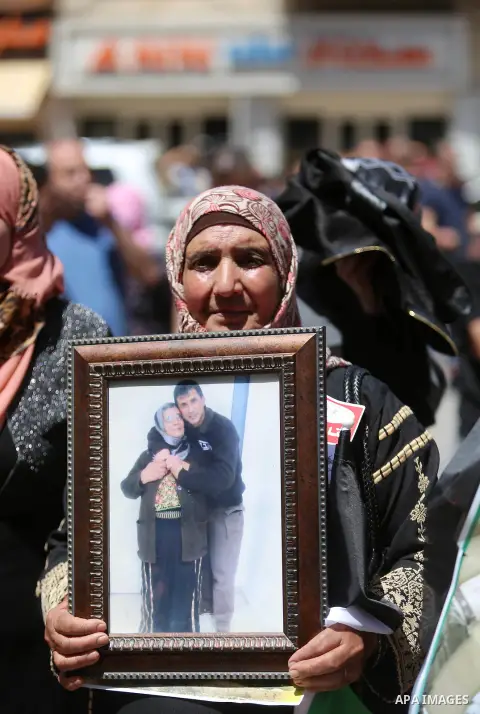 Palestinians hold pictures of Palestinians detained in Israeli prisons during a demonstration to mark Palestinian Prisoner Day in the West Bank city of Ramallah on April 17, 2016. Photo by Shadi Hatem