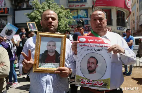 Palestinians hold pictures of Palestinians detained in Israeli prisons during a demonstration to mark Palestinian Prisoner Day in the West Bank city of Ramallah on April 17, 2016. Photo by Shadi Hatem