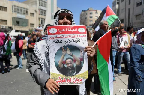 Palestinians hold pictures of Palestinians detained in Israeli prisons during a demonstration to mark Palestinian Prisoner Day in the West Bank city of Ramallah on April 17, 2016. Photo by Shadi Hatem