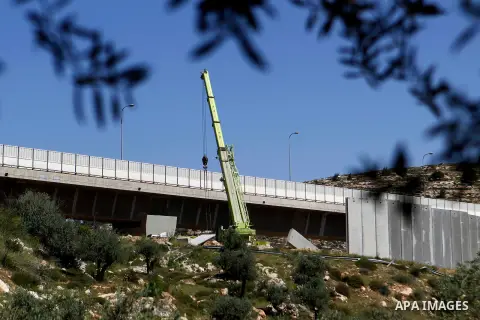 Israeli workers place a new section of Israel's separation concrete barrier in the Cremisan Valley, adjacent to the Christian Palestinian town of Beit Jala on April 17, 2016. The original route of the barrier was slated...