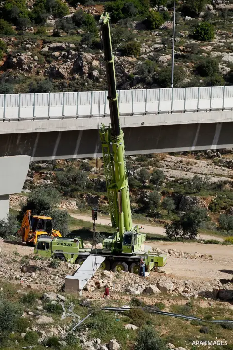 Israeli workers place a new section of Israel's separation concrete barrier in the Cremisan Valley, adjacent to the Christian Palestinian town of Beit Jala on April 17, 2016. The original route of the barrier was slated...