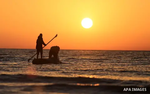 Palestinains ride a boat during sunset at the beach of the Mediterranean sea on the coast of Gaza city on April 17, 2016. Photo by Yasser Qudih